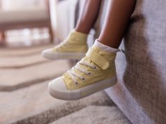 little,girls,legs,on,sofa,with,yellow,high,top,shoes