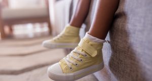 little,girls,legs,on,sofa,with,yellow,high,top,shoes