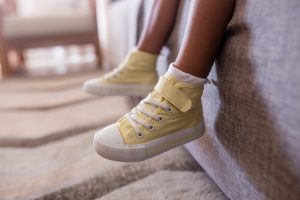 little,girls,legs,on,sofa,with,yellow,high,top,shoes