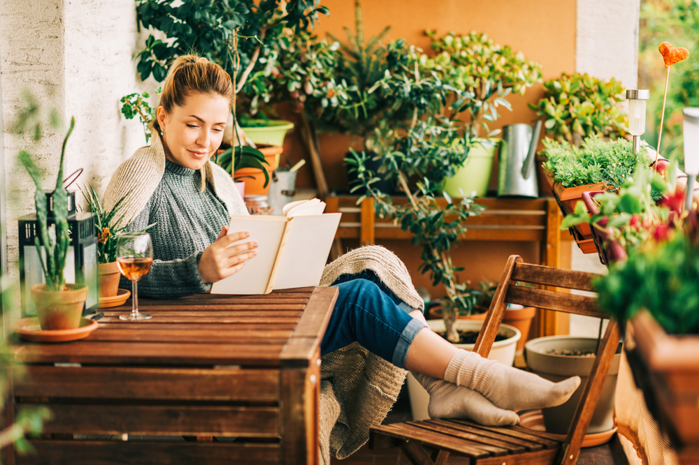 young,beautiful,woman,relaxing,on,cozy,balcony,,reading,a,book,